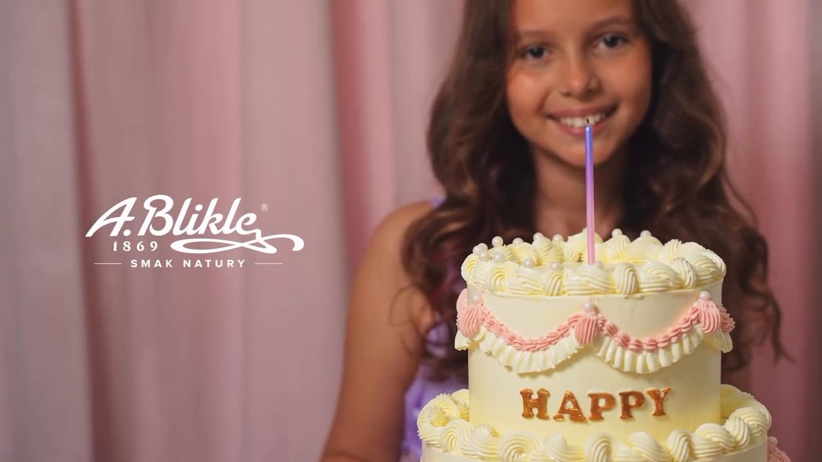 Kira smiling beside the A. Blikle campaign branding