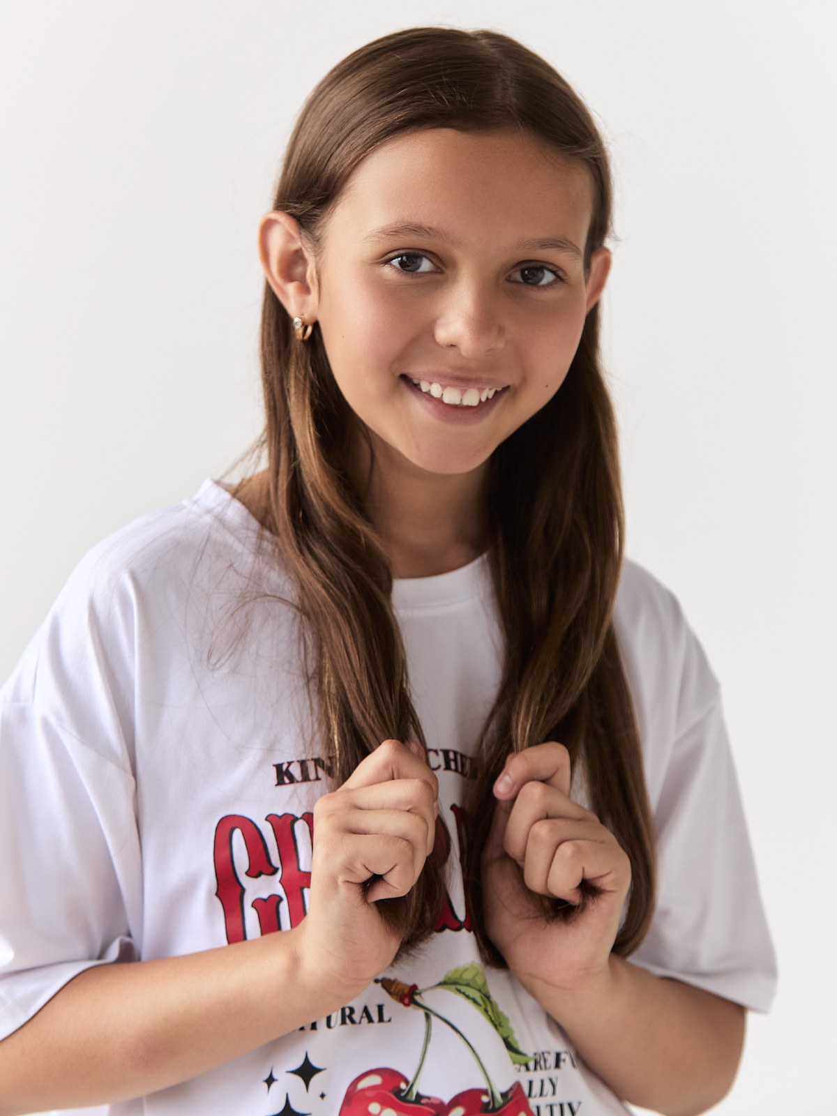 Natural smiling portrait of Kira in a white graphic T-shirt