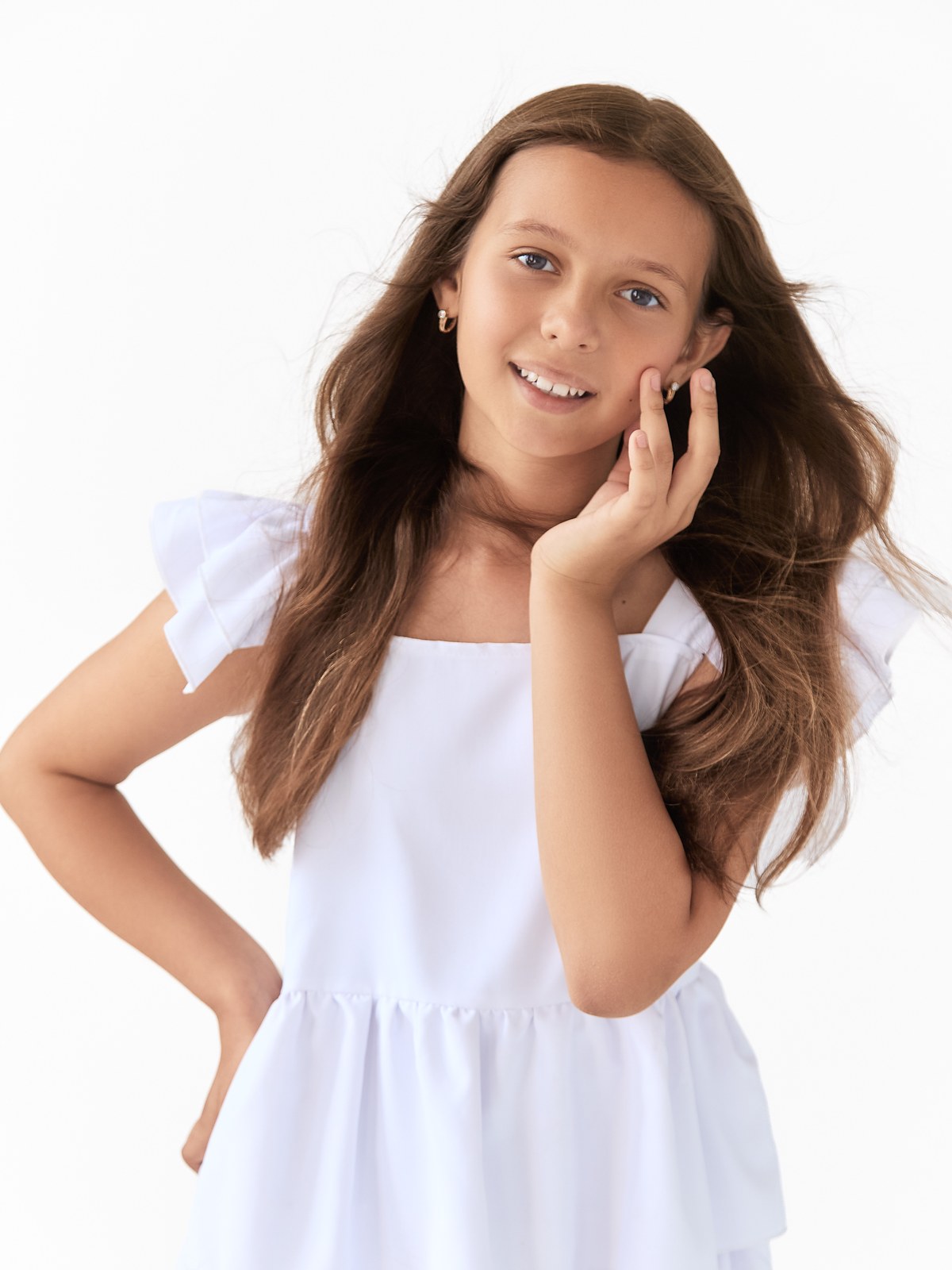 Kira smiling in a white dress in a bright studio portrait